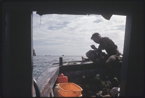 Fishing: giant clams (Tridacninae) on a boat, man holding on up in stern