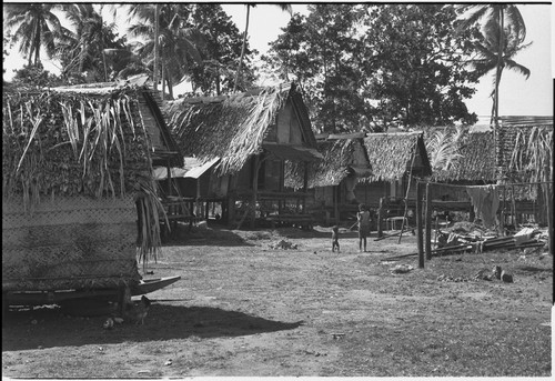 Tukwaukwa village, Kiriwina: houses, canoe under house (l), child and baby (center)