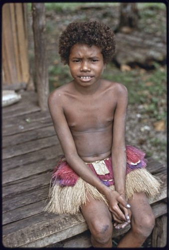 Girl wearing short fiber skirt sits on house veranda