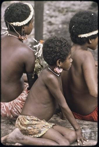 Girls wearing turtle shell earrings, armbands, and flower garlands