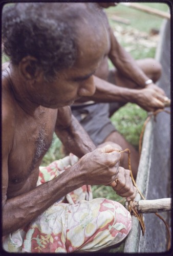 Canoe-building: men use lengths of vine to lash outrigger frame to a canoe