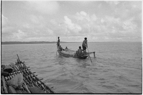 Canoes: men use poles to move small outrigger, detail of another canoe's platform in foreground