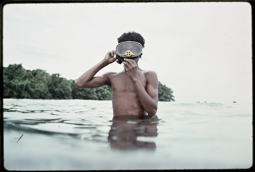 Man adjusts mask, preparing to dive