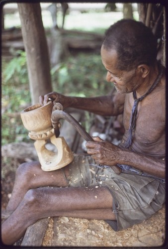 Carving: M'lapokala carving a bowl, probably for tourist trade, he uses an awl with carved wooden handle