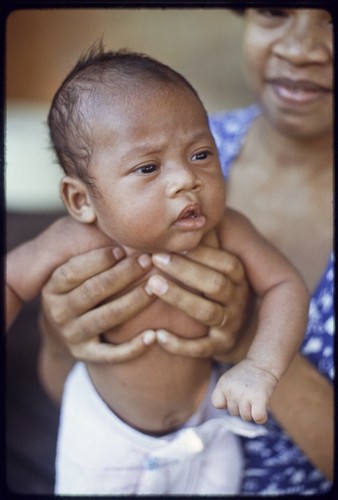 Proud mother holds up young infant wearing cloth diaper