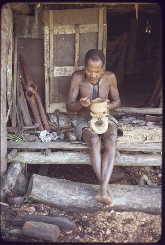 Carving: M'lapokala carving a bowl, other carvings on left are probably for tourist trade