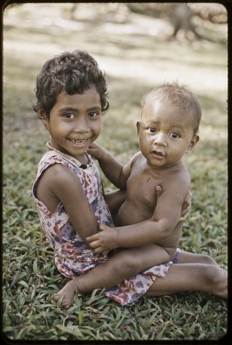 Young girl holding an infant, girl is smiling