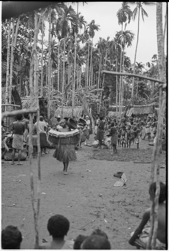 Mortuary ceremony, Omarakana: procession of mourning women carrying high-ranking fiber skirt valuables and large baskets, anthropologist Annette Weiner carries a banner