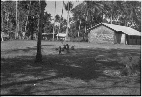 Village scene: church building (r), people carry bundles slung from poles