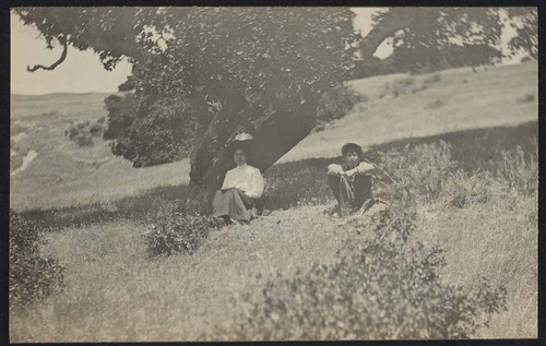 Child and woman longing under a tree