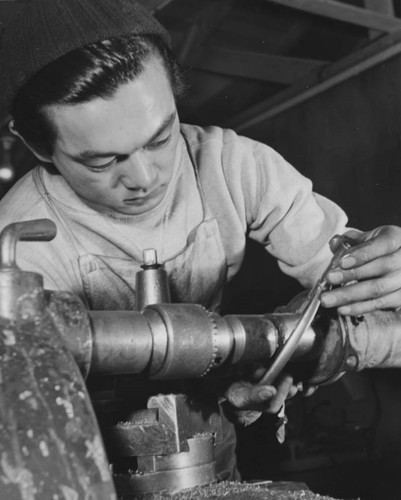 [Nisei machinist preparing a truck axle in machine shop at Heart Mountain incarceration camp]