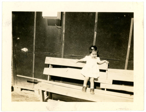 Baby girl standing on bench at incarceration camp