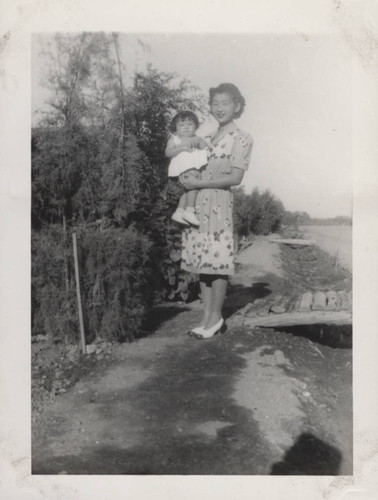 Woman in high heels holds an infant at Poston incarceration camp