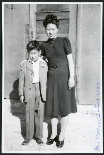 Photograph of Mrs. Moroika and son Ned posing in front of a door at Cow Creek Camp in Death Valley