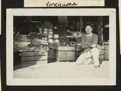 Shiego Takahashi kneeling in front of fruit stand