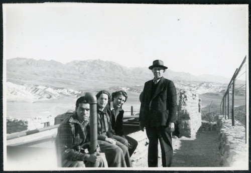 Photograph of four people next to Harmony Borax Works equipment in Death Valley