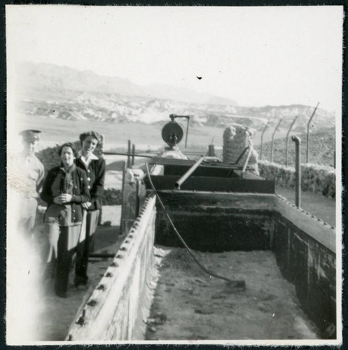 Photograph of three people standing next to Harmony Borax Works equipment in Death Valley