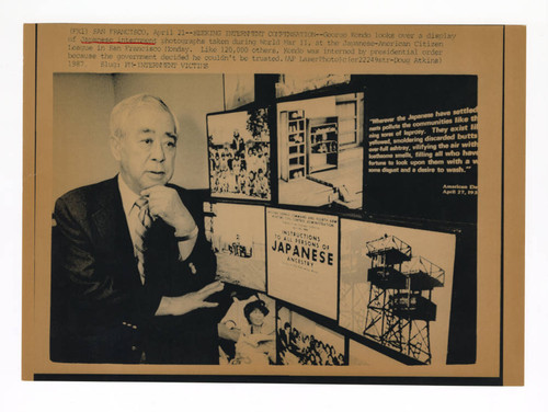 George Kondo near a display of photographs taken at incarceration camps during World War II
