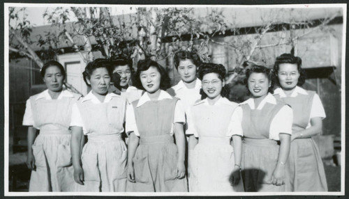 Photograph of eight hospital staff aides standing in front of the Manzanar hospital