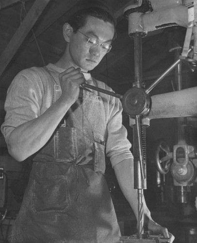 [Machinist operating drill press in motor pool shop at Heart Mountain incarceration camp]