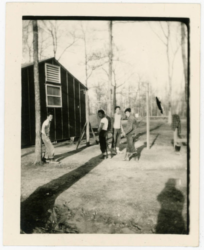 Young men standing by poles at incarceration camp