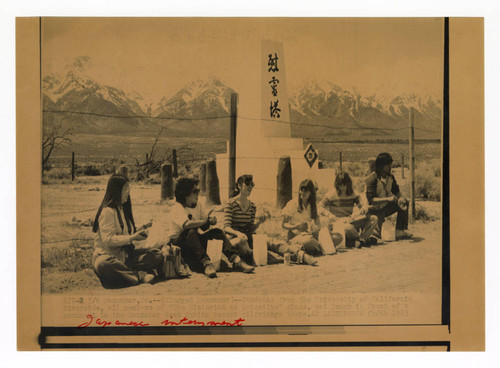 Students eat lunch in front of a monument at Manzanar