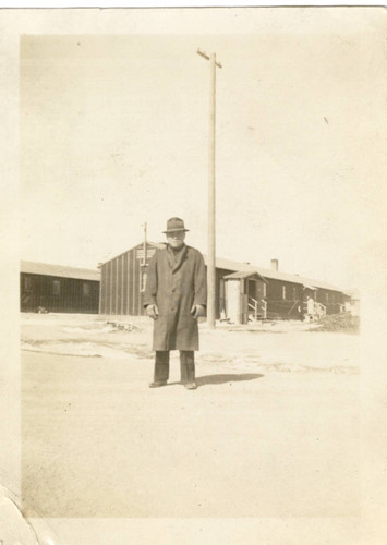 Man in front of camp barracks