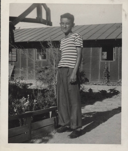 Teenage boy in striped shirt and cuffed pants at Poston incarceration camp