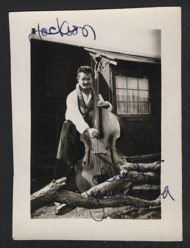 Member of the Paradise Melodiers band posing with a cello at Tule Lake