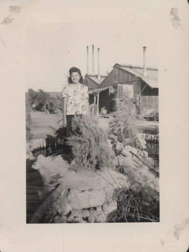 Woman in print shirt standing on island in pond at Poston incarceration camp