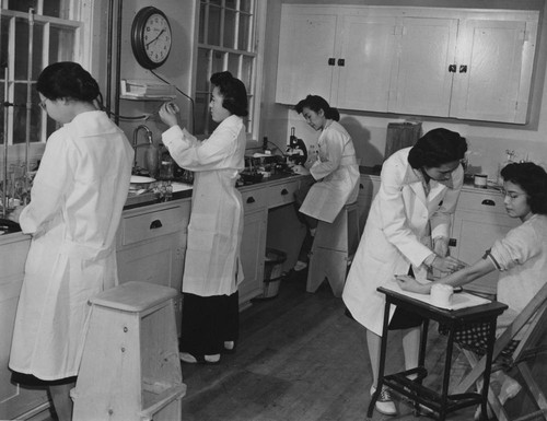 [Four technicians and a blood-test patient in hospital laboratory at Granada incarceration camp]