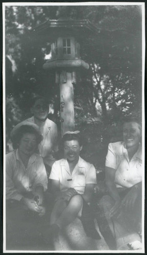 Photograph of four people, including L. Josephine Hawes, posing near a lantern at Manzanar