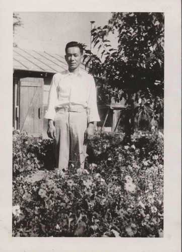 Man standing in flower garden at Poston incarceration camp