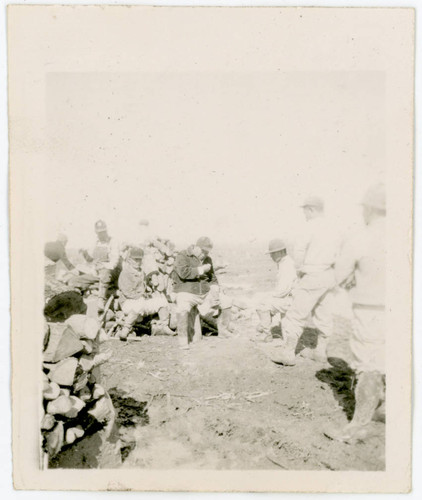 Men sitting around logs at incarceration camp