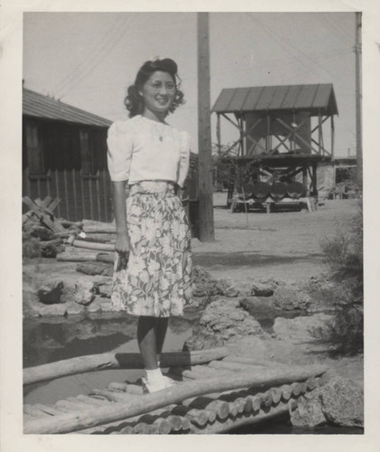 Young woman in flowered skirt on a footbridge at Poston incarceration camp