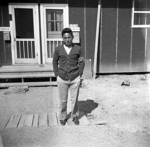 Nisei man in front of barracks in Jerome camp