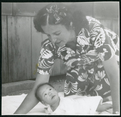 Photograph of Irene Gavigan leaning over an infant at Manzanar
