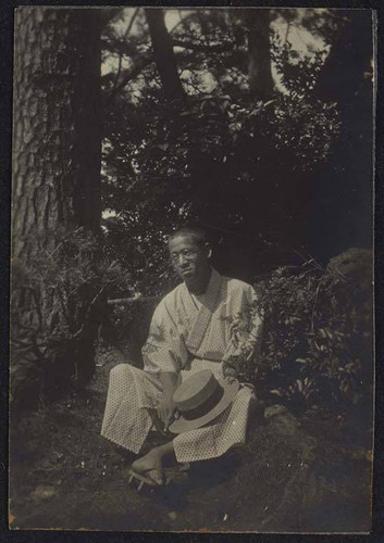 Man in kimono relaxing underneath trees