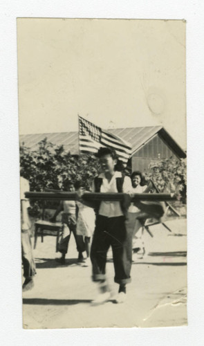 Nisei woman carrying a beam