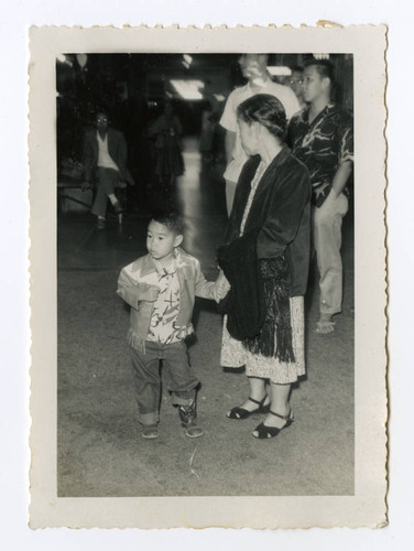 Woman holding young boys hand in airport