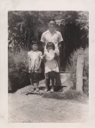 Man and two small girls in a garden at Poston incarceration camp