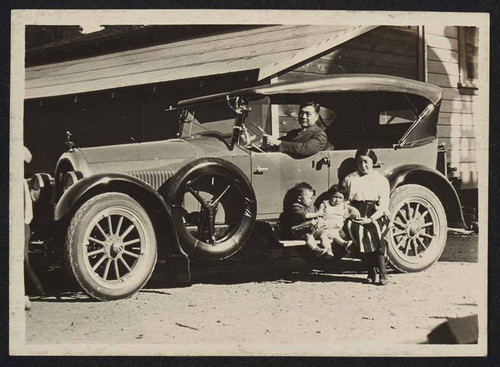 Man, woman, and children around car