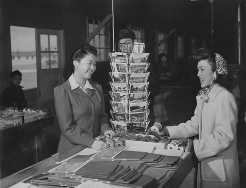 [Young Nisei girl purchasing Christmas wrappings in cooperative notion store at Granada incarceration camp]