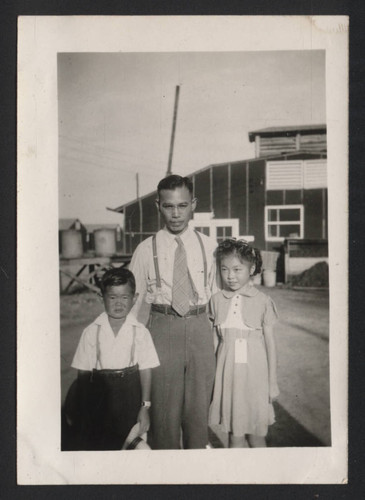 Father and children pose by the mess hall and kitchen at Jerome incarceration camp