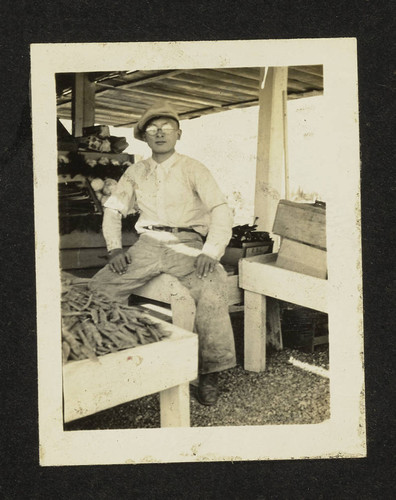 Shigeto Takahashi sitting near fruit stand