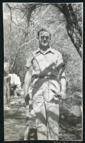 Photograph of a man standing under trees near Manzanar