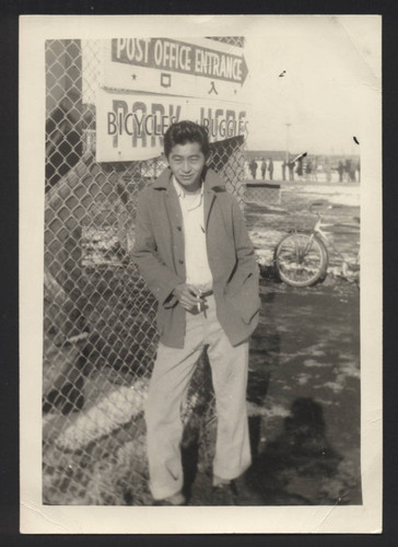 Suenari Koyasako standing by the Tule Lake post office fence