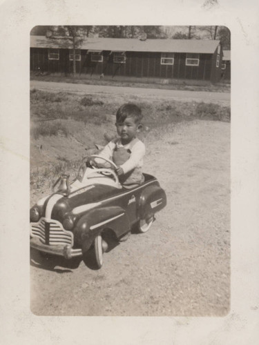 Boy in a Chief toy car at Poston incarceration camp