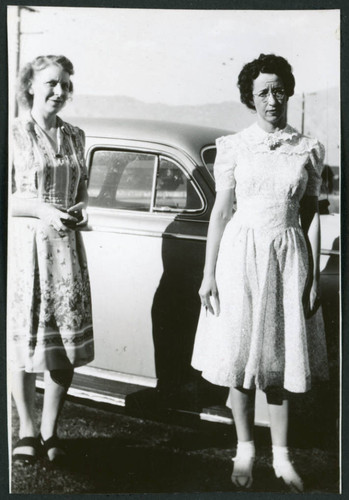 Photograph of women standing in front of a car