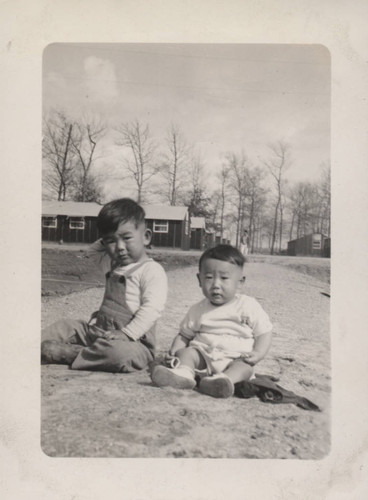 Baby and small boy sits on a path at Poston incarceration camp